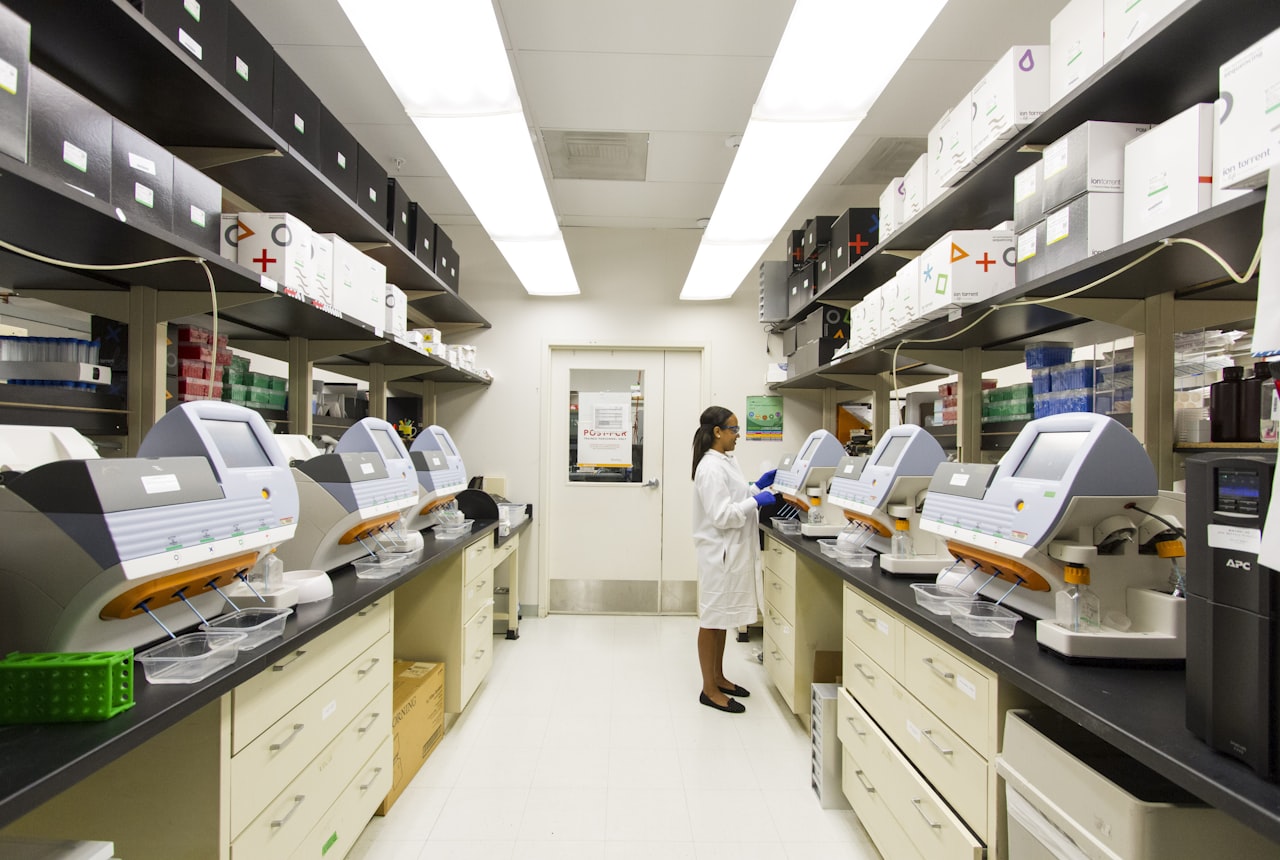 Technician working along a row of laboratory analysers