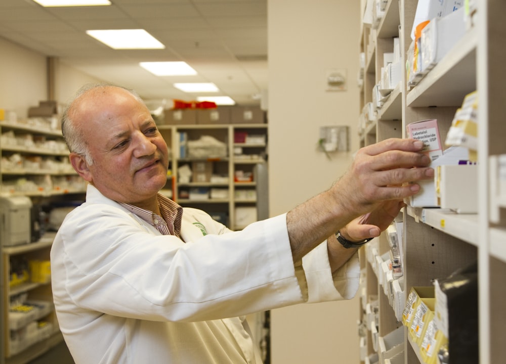 Pharmacist selecting medication from labelled shelving